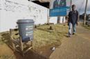 Un hombre camina frente a un balde que contiene agua clorinada como medida para contener la propagación del ébola en una calle en Monrovia, Liberia. EFE