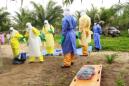 En esta foto tomada el viernes 19 de junio de 2015, los restos envueltos de un niño recién nacido sospechoso de contraer el virus ebola, descansan sobre una camilla mientras los trabajadores de salud, vestidos en equipo protector del ébola, mueven el cuerpo para un entierro en Dubreka, Guinea. A pesar de las esperanzas de que el mortal brote de ébola podría contenerse en el oeste de África, no muestra señales de disminuir en Guinea y podría estallar una vez más en Sierra Leona ya que la gente desobedece las reglas para contenerlo que limitan el viaje. (Foto AP/Youssouf Bah)